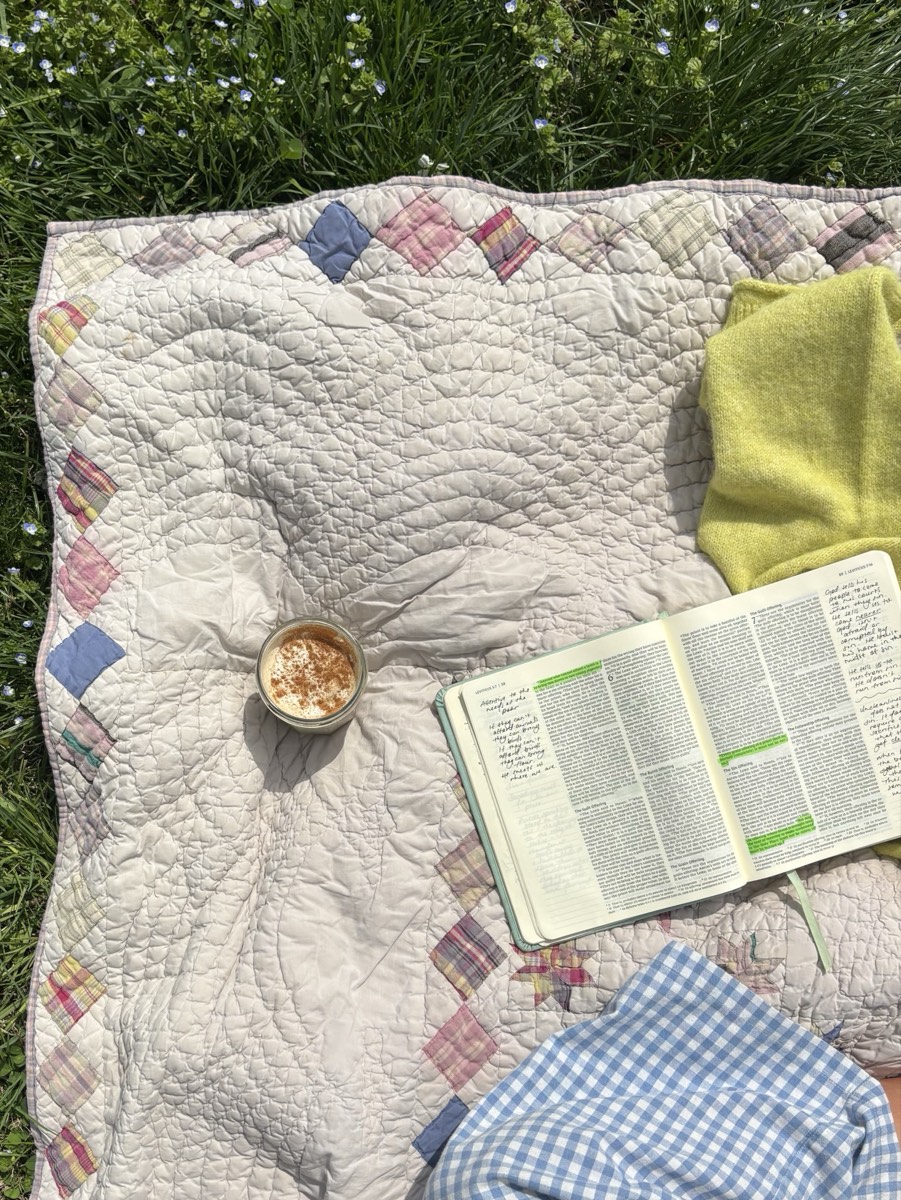 An open Bible on a quilt outdoors