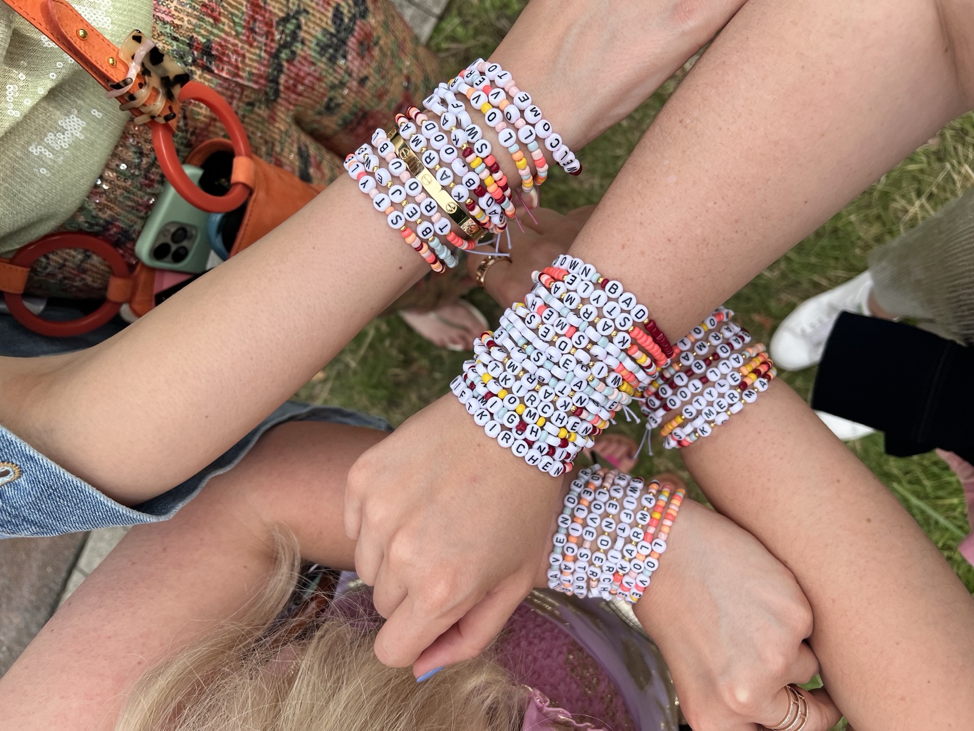 Friends with their arms stacked together, wearing friendship bracelets